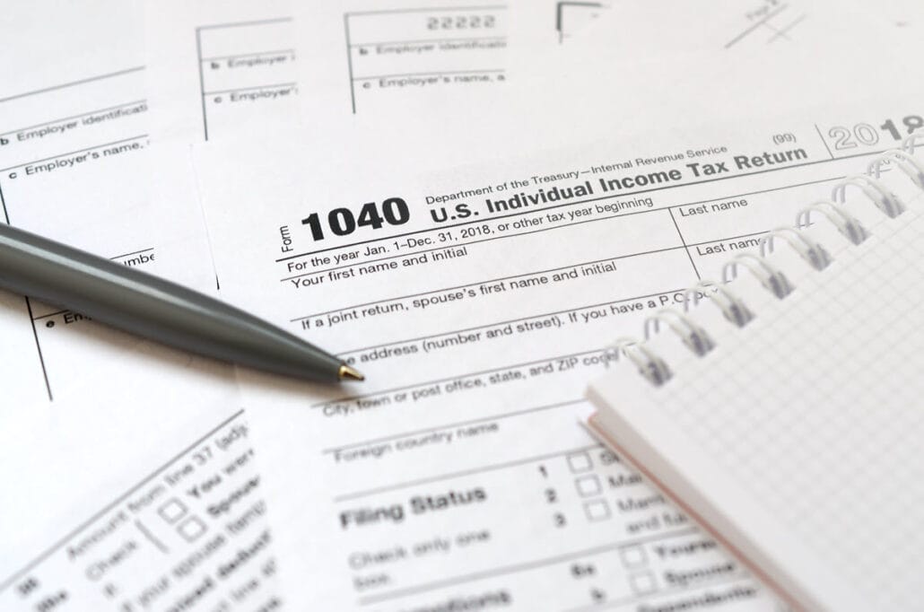 1040 tax forms next to a pen and a notebook.