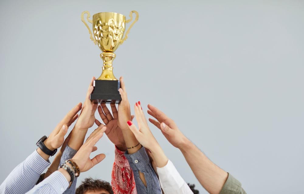 group of employees holding a trophy representing employee recognition enhancing workplace culture